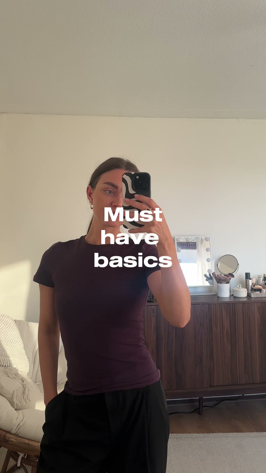 Sabine draagt een bruin basic shirt voor de spiegel